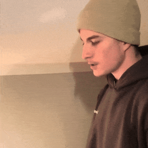 a man wearing a beanie and a hoodie with the word real on the sleeve