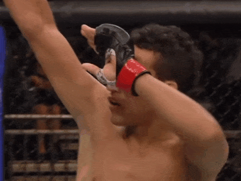 a man wearing a red and black boxing glove holds his arm up in the air