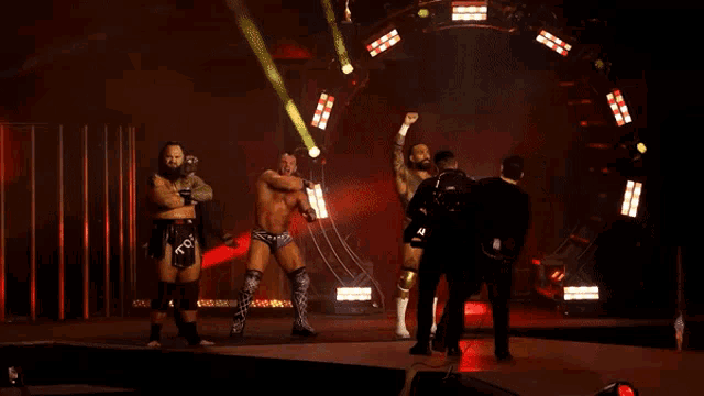 a group of wrestlers are standing on a stage and one of them has the letters tcw on their shorts