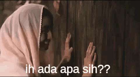 a woman in a pink hijab is touching a wooden door .