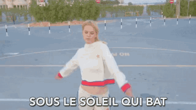 a woman in a white sweater and white shorts is dancing on a basketball court with her arms outstretched .