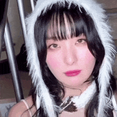a close up of a woman wearing a white furry hat and a necklace .