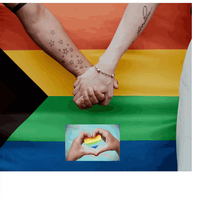 a couple holding hands in front of a rainbow flag with the word freedom on their arm