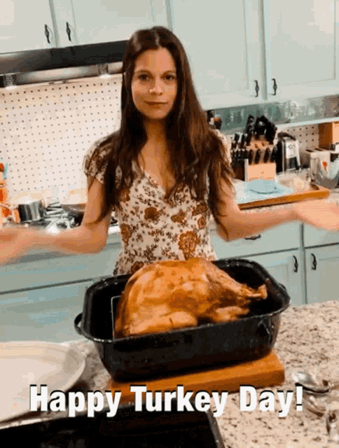 a woman in a kitchen with a turkey in a pan and the words happy turkey day