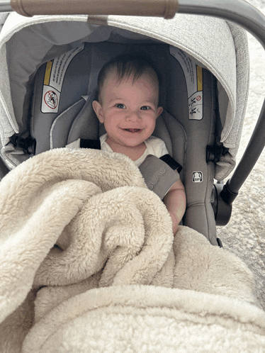 a baby is sitting in a car seat with a blanket covering him