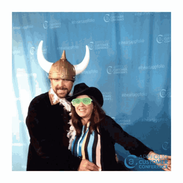 a man and a woman pose for a photo in front of a blue curtain that says appfolio customer conference