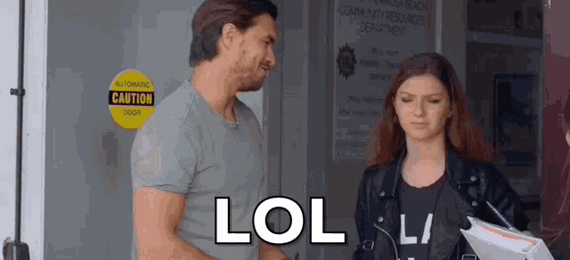 a man and a woman are standing next to each other in front of a door with a lol sign on it .
