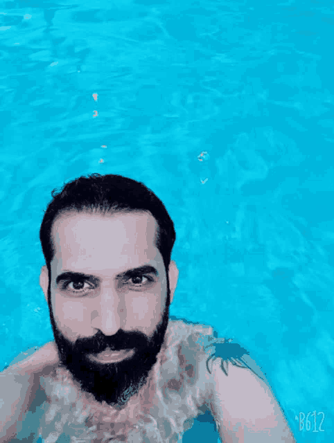 a man with a beard is swimming in a pool and his photo was taken with b612