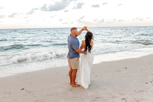 a man and woman are dancing on the beach