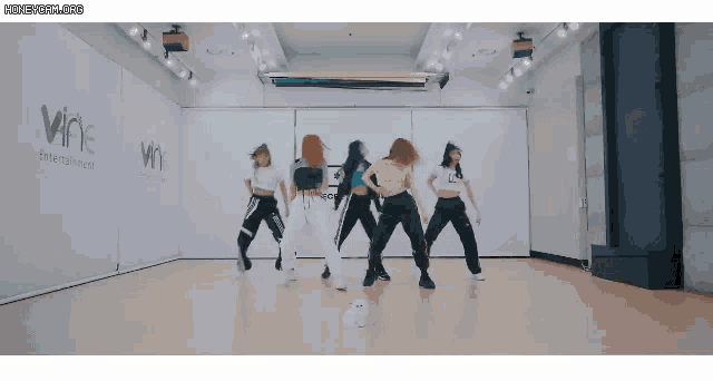 a group of women are dancing in a room with a sign that says wne