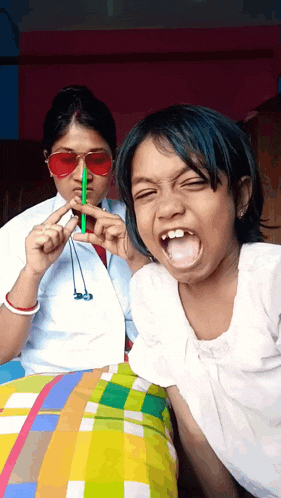 a girl wearing red sunglasses is holding a green straw
