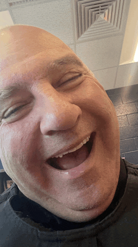 a bald man laughs with his eyes closed