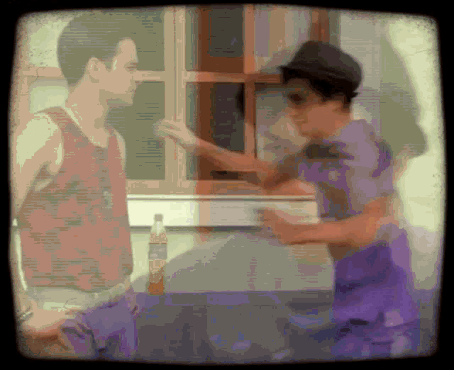 a man in a red tank top is talking to a woman in a purple shirt