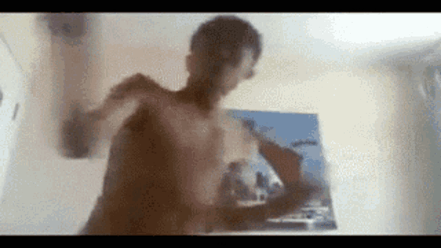 a shirtless man is standing in front of a painting on the wall .