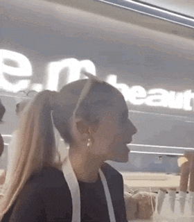 a woman wearing a ponytail is standing in front of a sign that says e.m. heart .