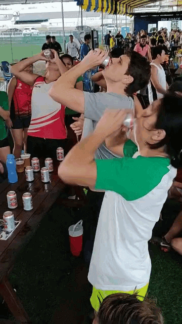 a group of people drinking beer at a picnic table in front of the snack bar