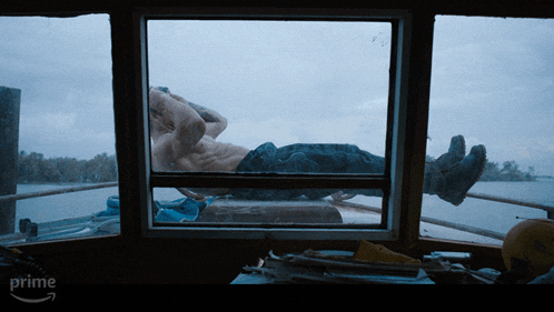 a man is laying on a boat in front of a window that says prime on the bottom