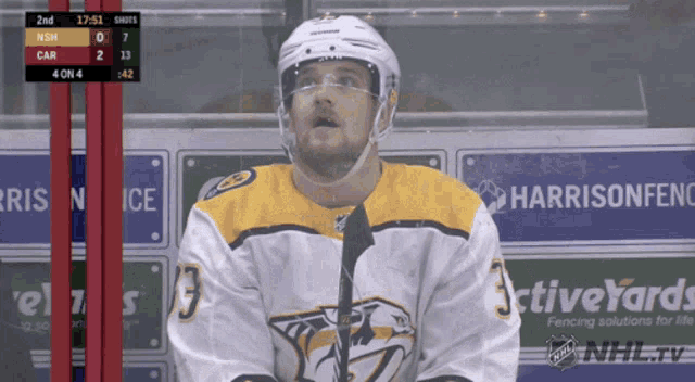 a hockey player stands in front of an advertisement for harrisonfence