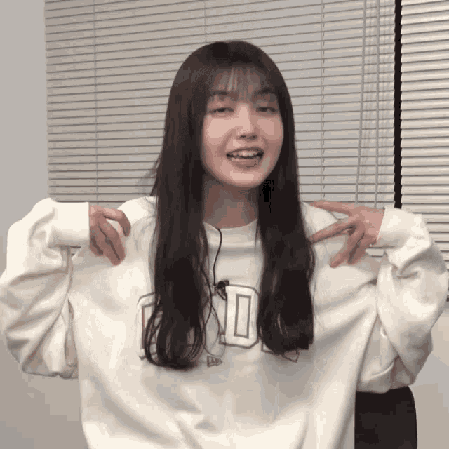 a woman wearing a white sweatshirt with the letter d on the front