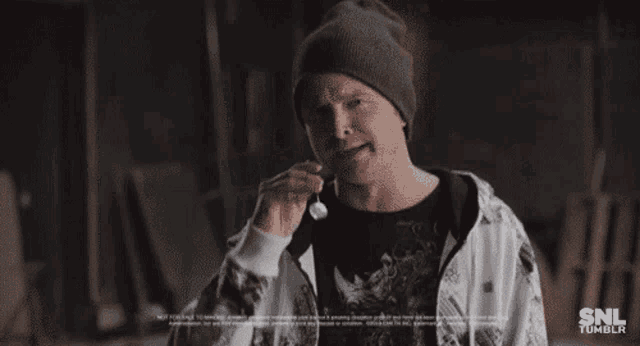a man wearing a beanie is drinking from a bottle with the letters snl tumblr on the bottom right