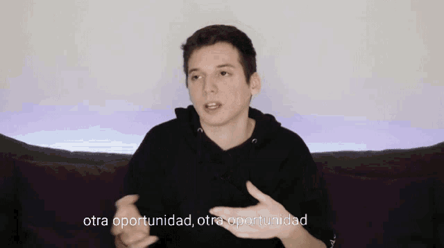 a young man sitting on a couch with purple pillows and the words otra oportunidad behind him