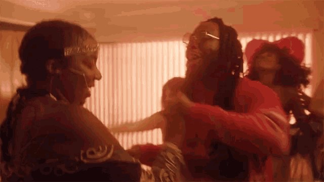 a group of people are dancing in a room with a red light behind them .