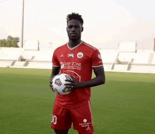 a soccer player is holding a soccer ball in front of a stadium .
