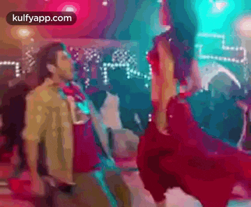 a man and a woman are dancing in a room with lots of lights .