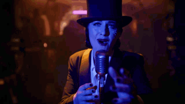 a woman singing into a microphone with a top hat on