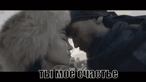 a man and a woman are kissing in front of a crowd in a video .