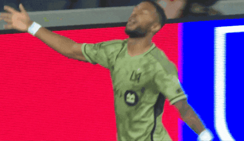 a soccer player wearing a green jersey with the letter l on the front