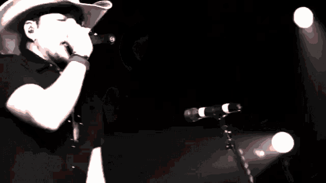 a man wearing a cowboy hat singing into a microphone
