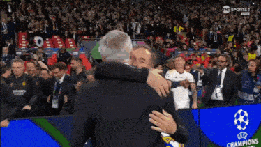 two men are hugging in front of a screen that says champions on it