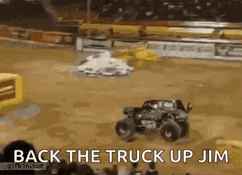 a monster truck is driving down a dirt track and a crowd is watching .