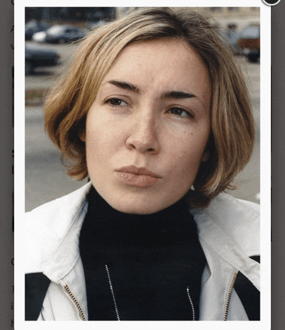 a close up of a woman 's face with a black turtleneck and a white jacket