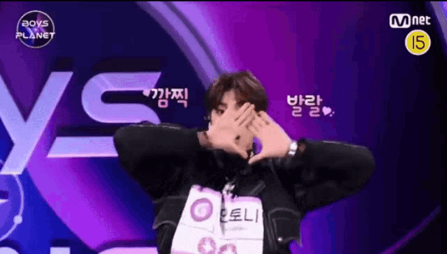 a man making a heart with his hands in front of a sign that says mnet