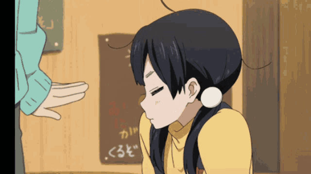 a girl in a yellow sweater is kissing a man 's hand in front of a sign with chinese writing on it