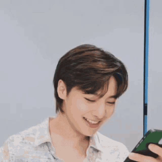 a young man is holding a cell phone and smiling .