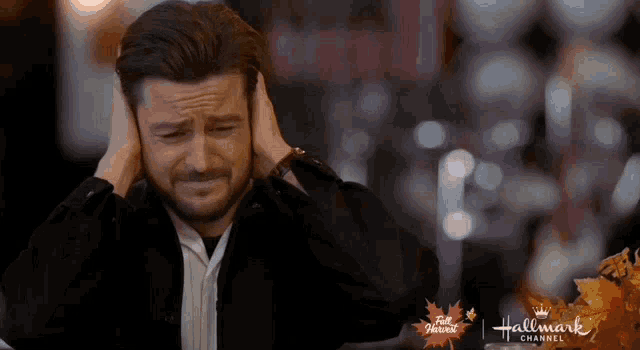 a man is covering his ears with his hands in front of a hallmark channel logo