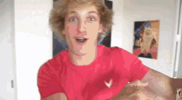 a young man in a red shirt is making a funny face in a room .