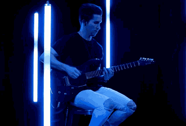 a man in a black shirt is playing a guitar