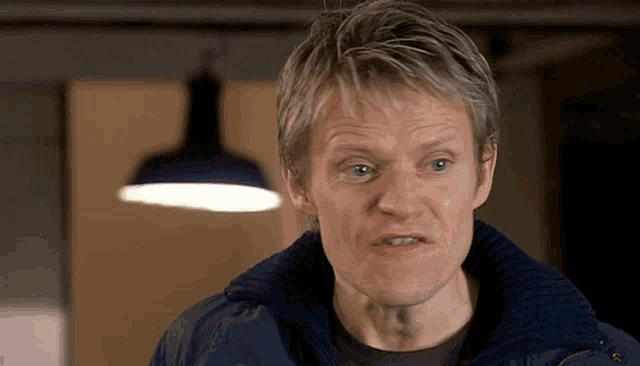 a man wearing a blue jacket looks at the camera