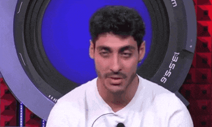 a man in a white shirt is sitting in front of a camera lens and making a funny face .