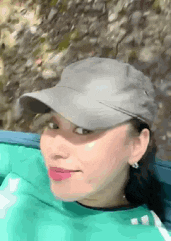 a close up of a woman wearing a hat and a green shirt