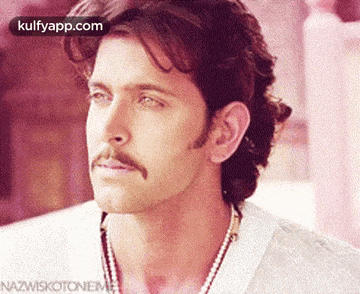 a close up of a man 's face with a mustache and a necklace .