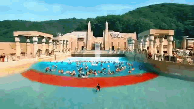 a group of people are swimming in a large pool in front of a building that has the word egypt on it