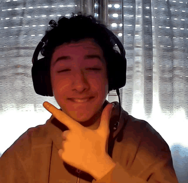 a young man wearing headphones and a microphone makes a peace sign