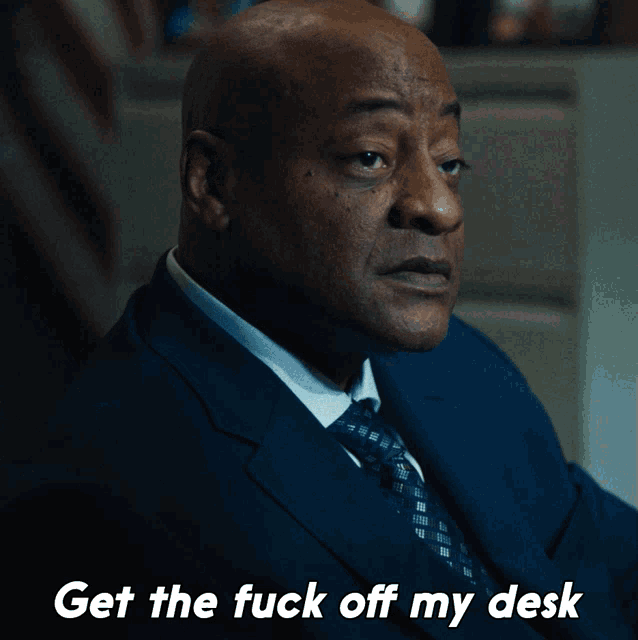 a man in a suit and tie has the words get the fuck off my desk below him
