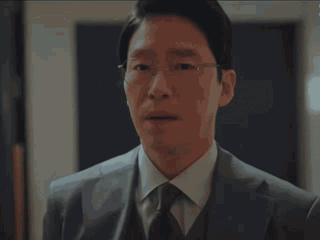 a man wearing glasses and a suit is making a face