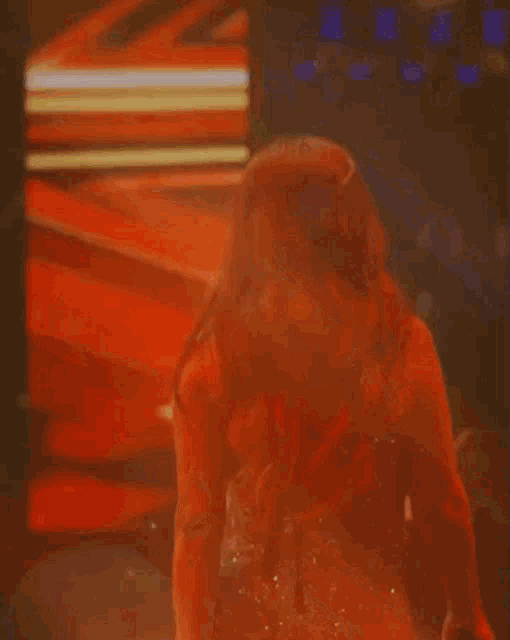 a blurred image of a woman with red hair standing in front of a red wall